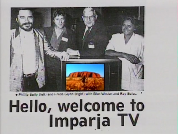 News article screengrab featuring three men and one woman leaning on a colour TV. Caption states Hello, Welcome to Imparja TV....